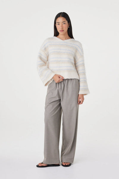A full-length studio look book shot capturing the model mid-stride at an angle. The movement emphasizes the fluid drape of the wide knit sleeves and the light, unrestrictive structure of the cropped sweater silhouette.