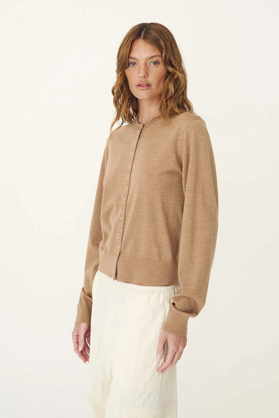 Three-quarter studio view of a model wearing the ROWIE Maeve Merino Spring Cardigan in Fawn Marle, showing the soft fit, round neckline, and fine button-front placket.