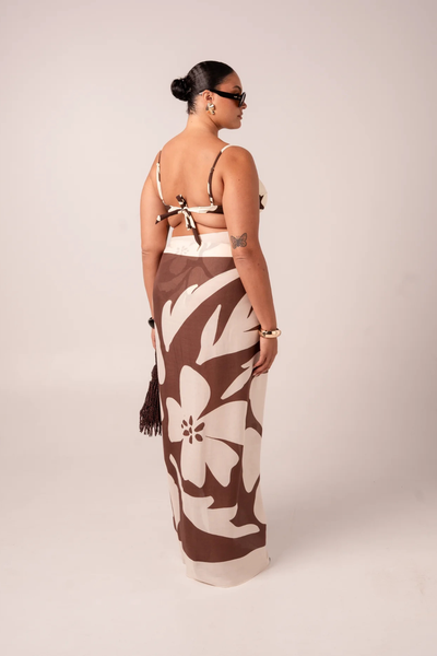 Back view of a model in studio setting wearing the tie-waist Ochre Lane Ibisco Sarong in brown and cream abstract hibiscus print.