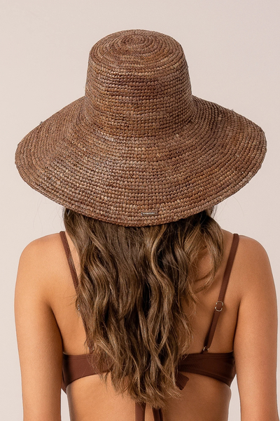 Back view of a model showcasing long brown hair and the back of the structured, wide-brim cocoa raffia bucket hat.