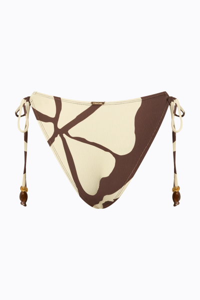 Flat product shot of the back of the Ochre Lane bikini bottom in the Ibisco abstract floral print against a clean white background, showcasing the adjustable side ties with bead details and a small branded metal hardware tag at the back waistband.