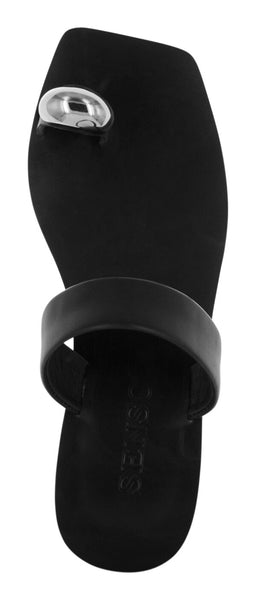 A top-down studio shot of a single Senso Olga flat slide sandal in ebony black calf leather. The minimalist design showcases a sleek square-toe footbed, a thick midfoot leather strap, and a distinct leather toe loop adorned with a smooth, oversized metallic dome embellishment.