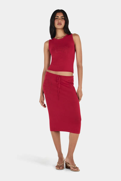 Three-quarter studio view of model wearing the red Ownley Inka knitted tank top with pointelle floral detail, paired with the matching Vesna Midi Skirt and tan mules.