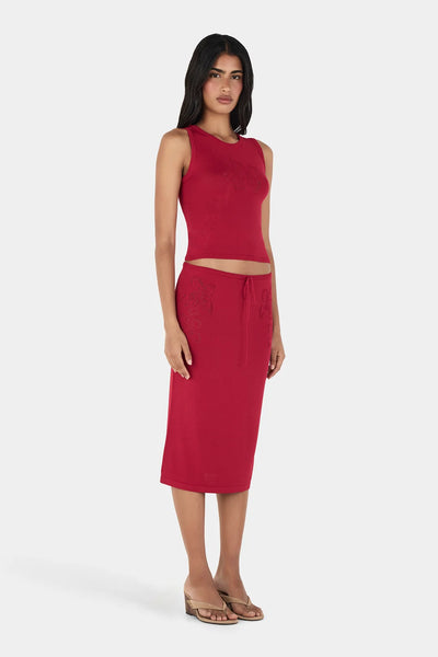 Slight angle studio shot of model wearing the red Ownley Inka knitted crew neck tank top and Vesna midi skirt set with pointelle knit details.