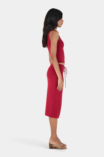 Side profile view of model showcasing the fitted silhouette of the Ownley Inka Top in Lipstick with matching red knit skirt and heeled slide sandals.
