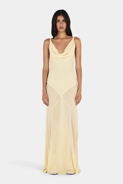 Studio full-length front view of a model wearing a light butter yellow draped cowl neck gown with a panelled bias skirt reaching the floor.