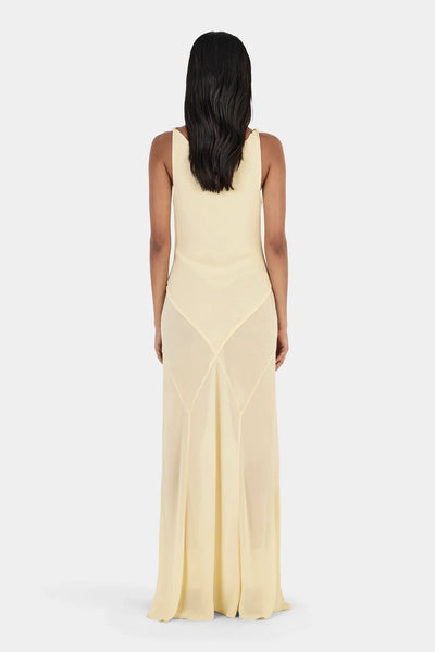 Studio rear full-length view of a model wearing a butter yellow floor-length gown showcasing the panelled bias seams and low scoop back.
