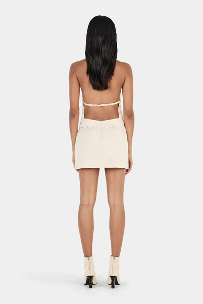 Full rear view of model wearing the cream Ownley Sammie Mini Dress, highlighting the open back cut-out design with an adjustable strap and belt loops.