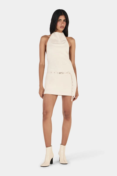 Full-length front view of model wearing the cream-colored Ownley Sammie halter mini dress, styled with off-white heeled ankle boots.