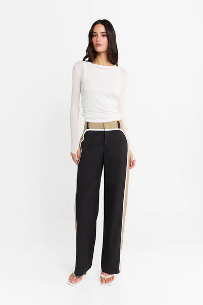 Studio front-facing view of a model wearing the white Kova top and color-blocked trousers against a clean white background.