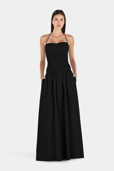 Full-length studio front view of a model wearing a black halter-neck maxi dress featuring a sweetheart-contoured smocked bodice and a flowing maxi-length skirt.