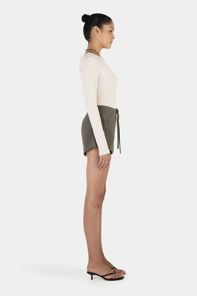 A side profile studio shot illustrating the elongated, slim-fitting design of the sleeves, which measure 73.5cm on a size small to allow for a comfortable, gathered look around the wrists.