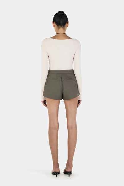 A full back view of the cream long sleeve top on a model, showcasing the clean, contoured seam lines across the shoulders and back torso that emphasize the body’s silhouette.