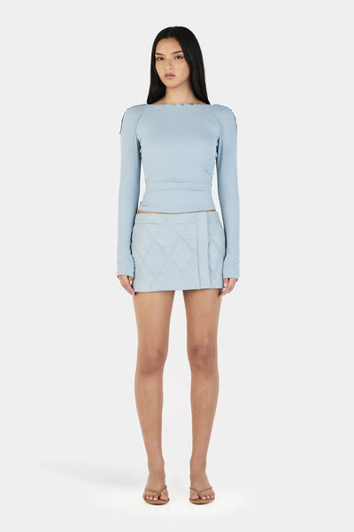 A front portrait studio view of a model wearing the Ownley Quinn Long Sleeve Top in Ice Blue, highlighting the smooth, sculpted fit of the soft ribbed jersey fabric and the wide boatneck-style neckline sitting comfortably on the shoulders.