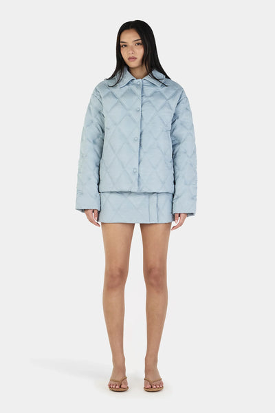 A closer front studio image of the ice blue puffer jacket, highlighting the structured look of the unique angled collar when fully fastened.