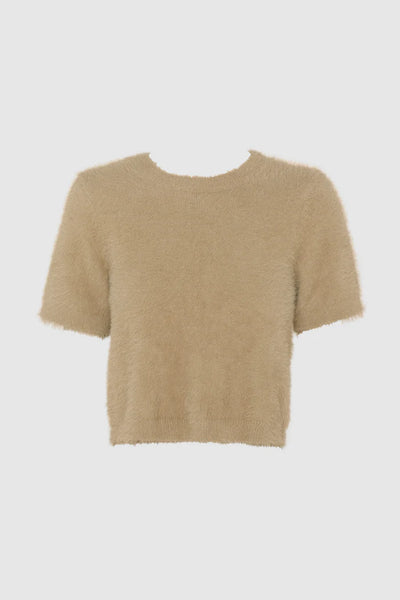 A full-length studio profile shot from the rear angle, showcasing the clean back drape and short-sleeve construction of the fluffy knit tee, styled with tailored high-waisted cream trousers and black pointed-toe heels.