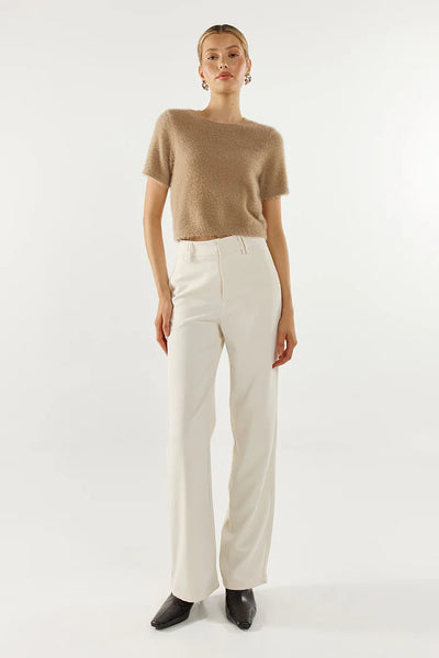 A full-length front studio shot of a model presenting the fluffy knit tee, emphasizing its comfortable scooped neckline and sophisticated look when paired with wide-leg white trousers.
