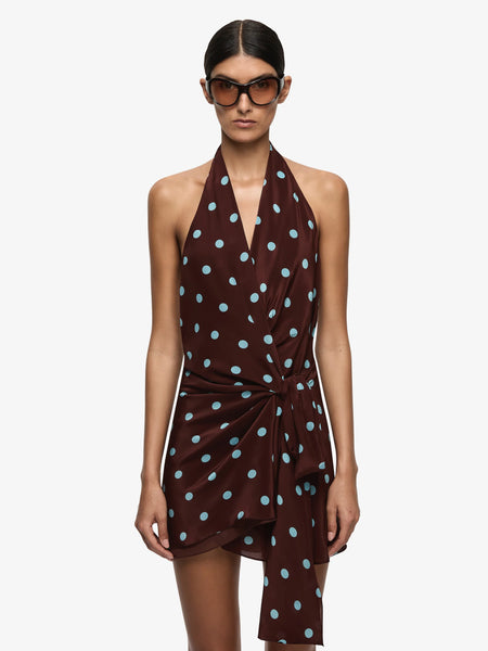 A close-up front view focusing on the upper torso of the model wearing the halter neck mini dress, showcasing the soft gathering at the neckline, the deep V-front crossover draping, and the central waist tie construction.