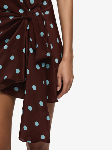 A cropped front detail shot focusing on the waist and hip area, emphasizing the intricate wrap-knot detailing, the regular spacing of the blue polka dot print, and the drape of the long side-tie accent panel.