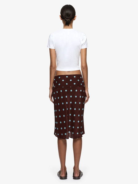 A full-length rear view of the model from behind, demonstrating how the viscose-silk blend bias-cut fabric contours smoothly over the hips and flows down to a clean knee-length hem.