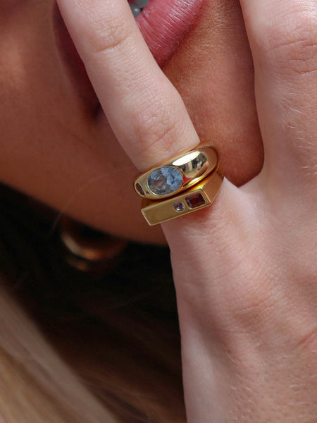Close-up detail shot of the Jessica ring and a companion ring worn on a finger resting near the face.