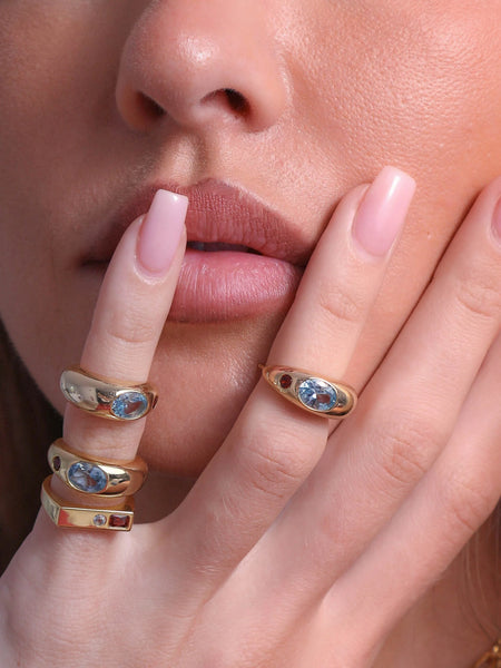 Macro close-up shot showcasing the rectangular signet face of the Jessica ring and a matching gemstone ring stacked together near the lips.