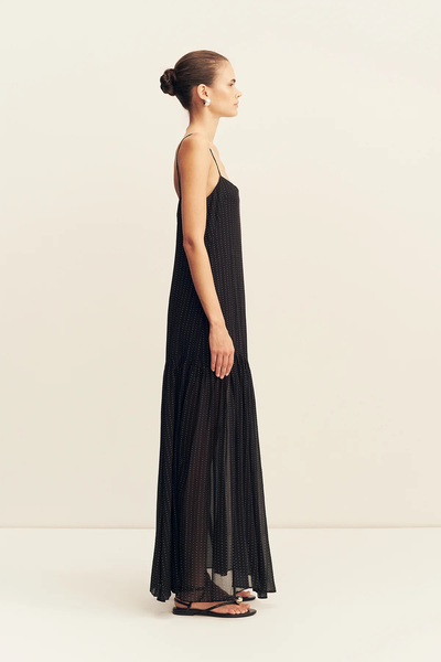 Side profile view of a model wearing the sleeveless Shona Joy Irving Polka Dot Maxi Dress in Black Polka Stripe.