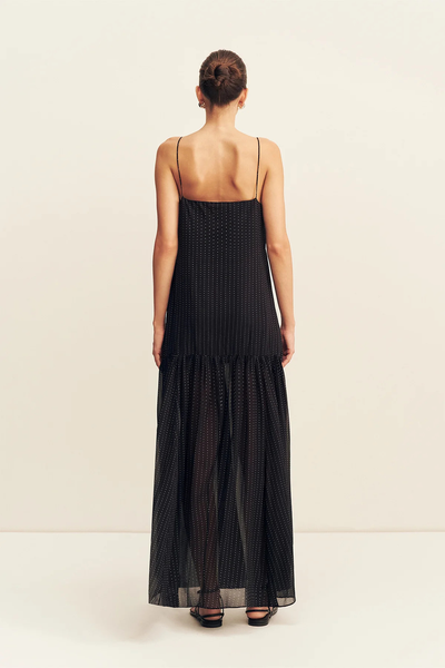 Full back view of a model wearing the Shona Joy Irving Polka Dot Maxi Dress in Black Polka Stripe highlighting the straight back neckline and sheer maxi skirt overlay.