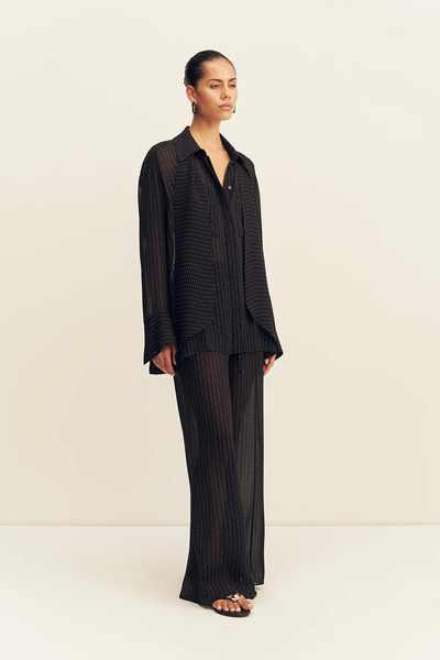 Three-quarter side angle of a model wearing the relaxed-fit Shona Joy Irving Polka Dot Sheer Pant in Black Polka Stripe in semi-sheer georgette.