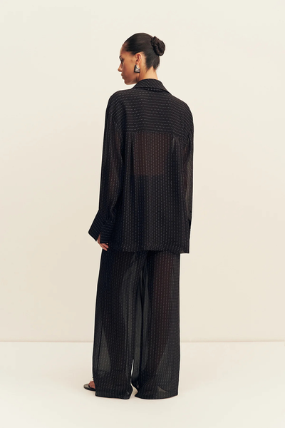 Three-quarter back view of a model wearing the Shona Joy Irving Polka Dot Sheer Pant in Black Polka Stripe with matching oversized shirt.