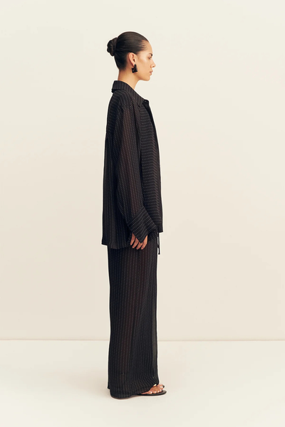 Side profile shot of a model wearing the wide-leg Shona Joy Irving Polka Dot Sheer Pant in Black Polka Stripe.