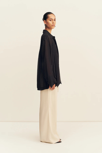 Side profile studio shot of a model wearing the long-sleeve Shona Joy Irving Polka Dot Sheer Shirt in Black Polka Stripe.