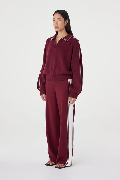 A full-length studio product shot capturing the model from a three-quarter angle to showcase the comfort-focused fit, straight leg drapery, and the side stripe detail.