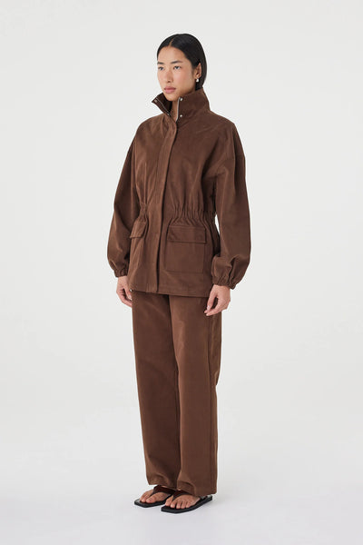 A three-quarter studio product shot with the model turned slightly, showcasing the clean lines of the funnel neck detail and the soft shape of the jacket's profile.