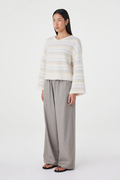 A three-quarter studio product shot with the model turned slightly to the right. The perspective highlights the easy fit through the body, the low-profile dropped armhole design, and how the cropped hem sits comfortably above the waistline of the coordinated tailoring.