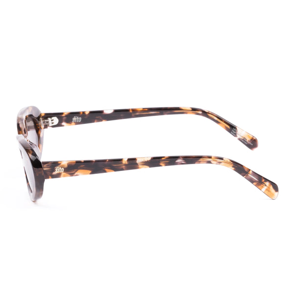 Side profile studio image of the Sito Shades Lourdes oval sunglasses in pebble tort displaying the slim acetate temples and silver hardware logo detailing.
