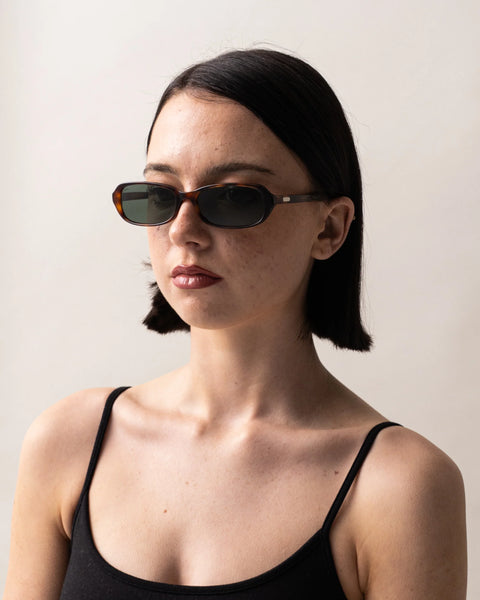 Three-quarter portrait of a female model wearing the Sito Shades Roux sunglasses in translucent Classic Tort acetate against a light grey background.