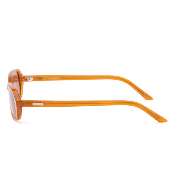 Side profile studio image of the Sito Shades Roux sunglasses in translucent caramel orange acetate highlighting slim temple arms with silver brand logo detailing.