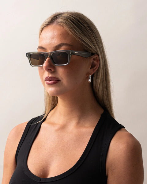 Three-quarter portrait of a blonde model wearing the Sito Shades Vincent rectangular sunglasses in translucent Nori green acetate with brown polarised lenses.