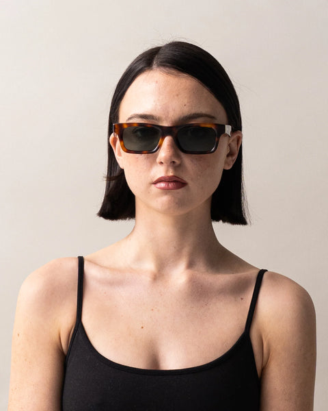 Front portrait studio shot of a dark-haired model wearing the Sito Shades Vincent rectangular sunglasses in classic tortoiseshell acetate paired with a black camisole.