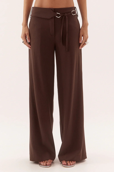 Front croppage studio view of a model wearing dark chocolate mid-rise straight-leg trousers showcasing a wide waistband and a removable tie-belt with silver D-ring hardware.