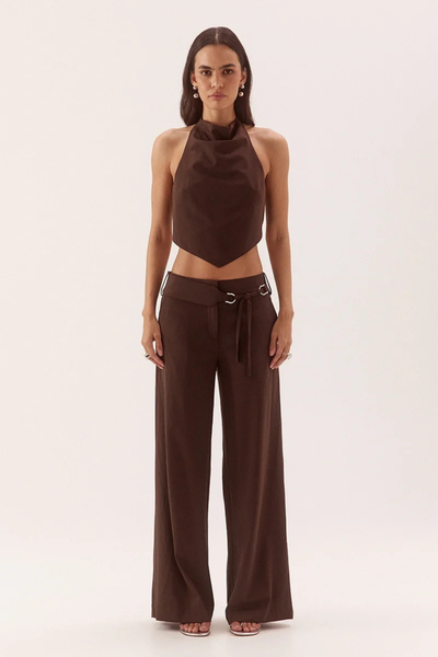 Full-length studio front view of a model wearing dark chocolate brown straight-leg tailored trousers styled with a matching cowl-neck halter top and silver sandals.