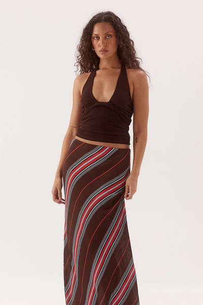 Studio front view of a model wearing a dark chocolate brown halter top featuring a deep scoop neck and gathered bodice, styled with a brown diagonal stripe maxi skirt.