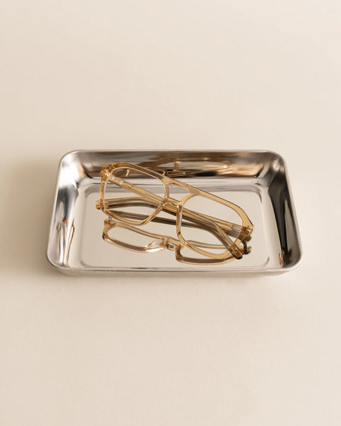 Flat-lay product photography of Sito Shades The Void Blue Light glasses in Sunlight displayed inside a polished silver metal tray.