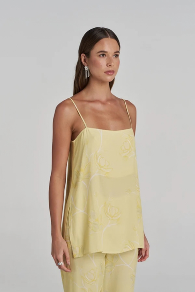 Studio side profile view of a model wearing the magnolia yellow floral tunic top, highlighting the straight neckline and relaxed fit.