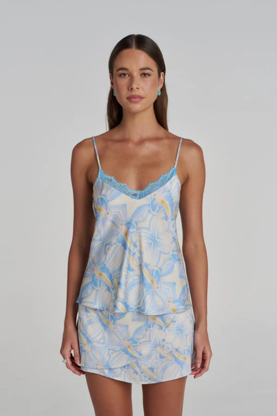 Close-up studio front view of a model wearing the blue and white patterned camisole with delicate blue lace trim along the V-neckline.