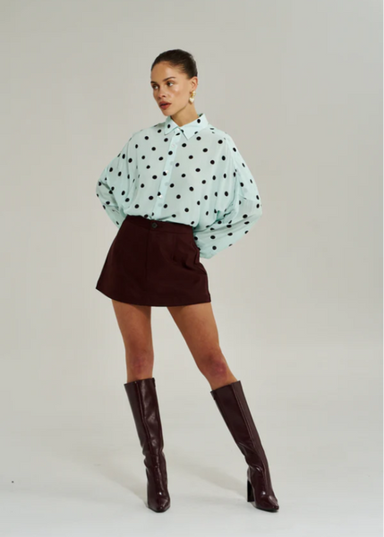 Model wearing the Summi Summi A-line skirt in Syrah, showcasing the clean waistline and the way the fabric flares slightly for ease of movement.