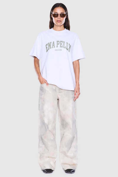 Full-length studio front shot of a model wearing a white marle crew-neck graphic tee paired with wide-leg trousers.