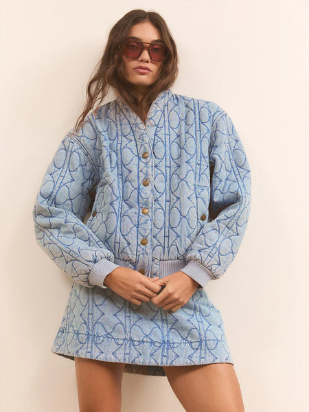 A front lifestyle studio image of the heavy-weight quilted jacket styled open over a white tank top, emphasizing its relaxed, off-duty drape against the body.