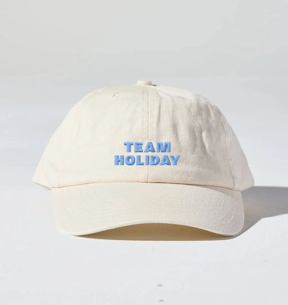 A front studio view of the 6-panel unstructured Team Holiday Cap, showcasing the hard, fully curved peak and custom holiday-themed embroidery on the crown.